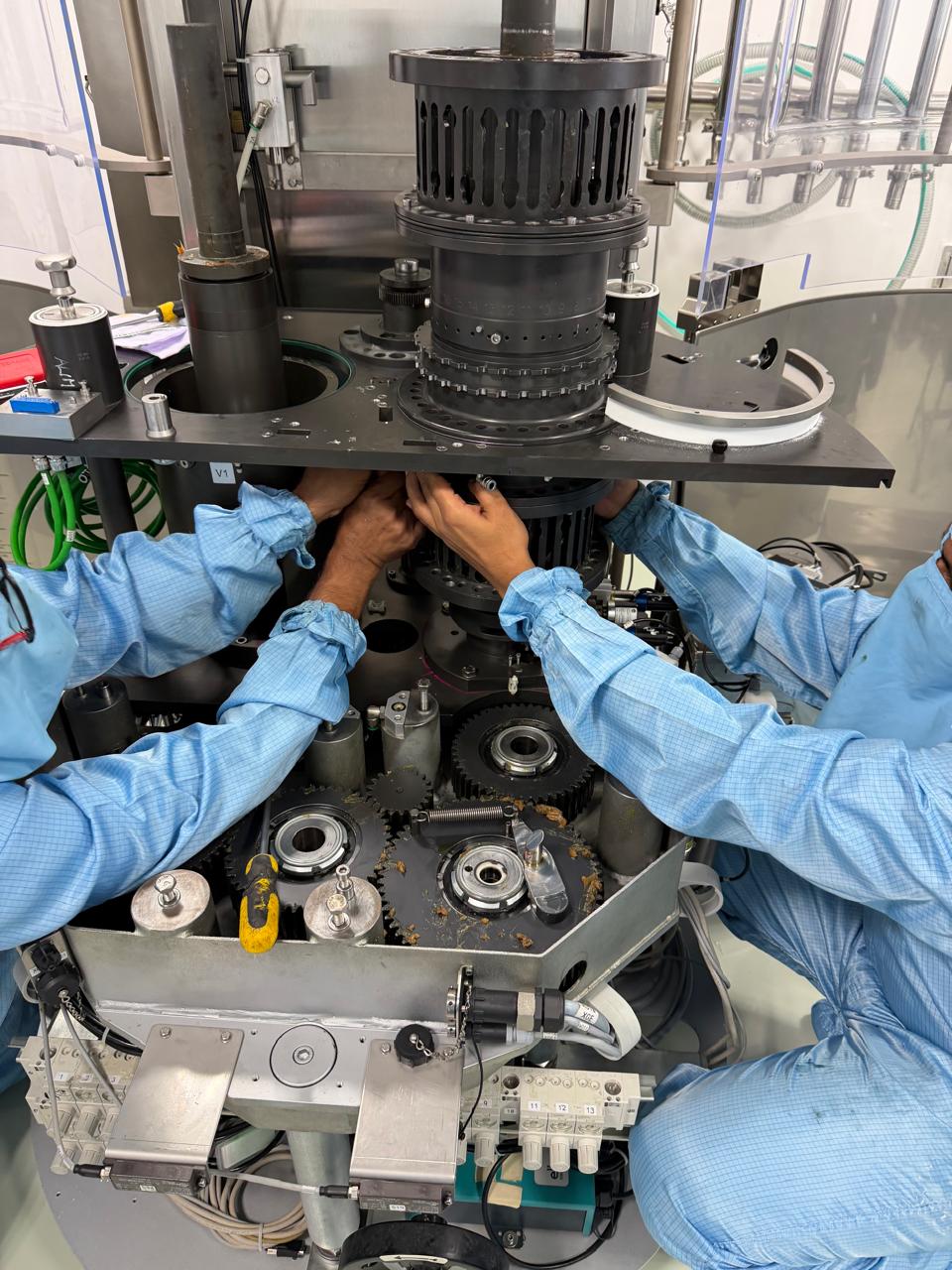 Engineers servicing capsule filling machinery in a cleanroom